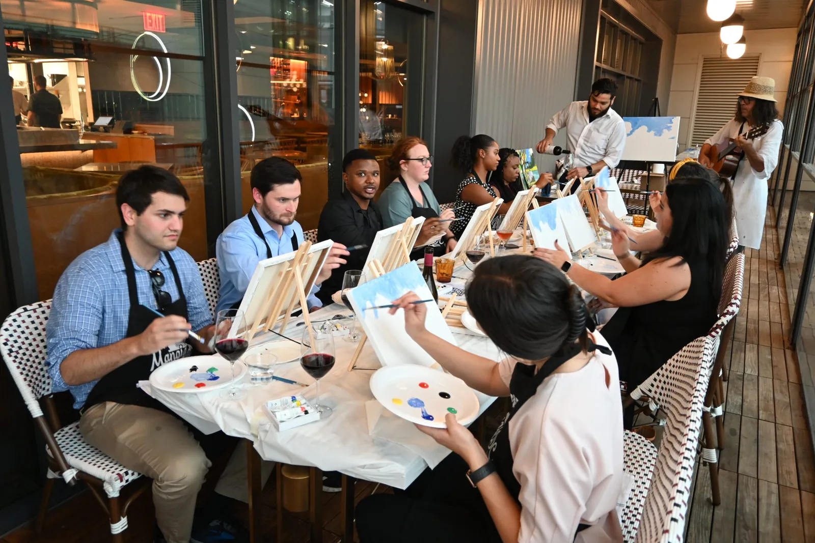 Corporate team painting canvases with wine at a private paint and sip event