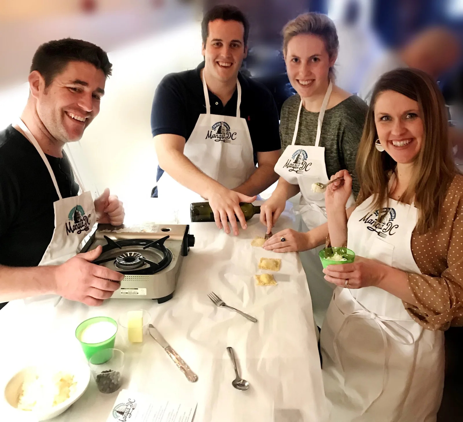 Four coworkers in aprons cooking together at a private group cooking class