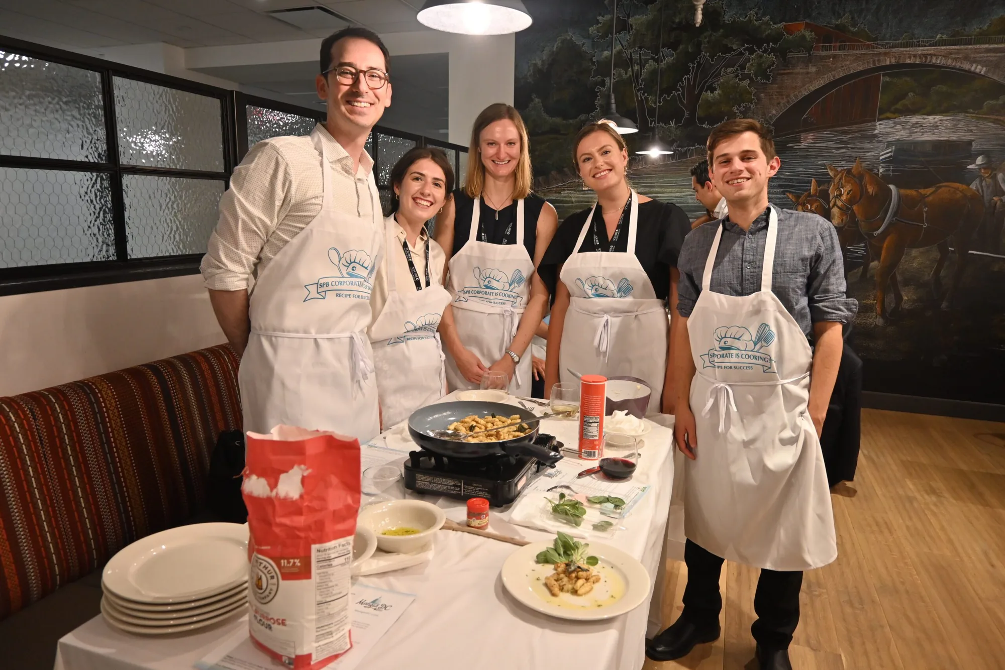Group in Mangia DC aprons at a cooking station during a private cooking class in Washington, DC