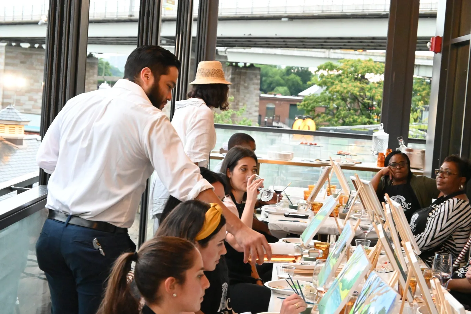 Long table of guests painting step by step at a group paint and sip