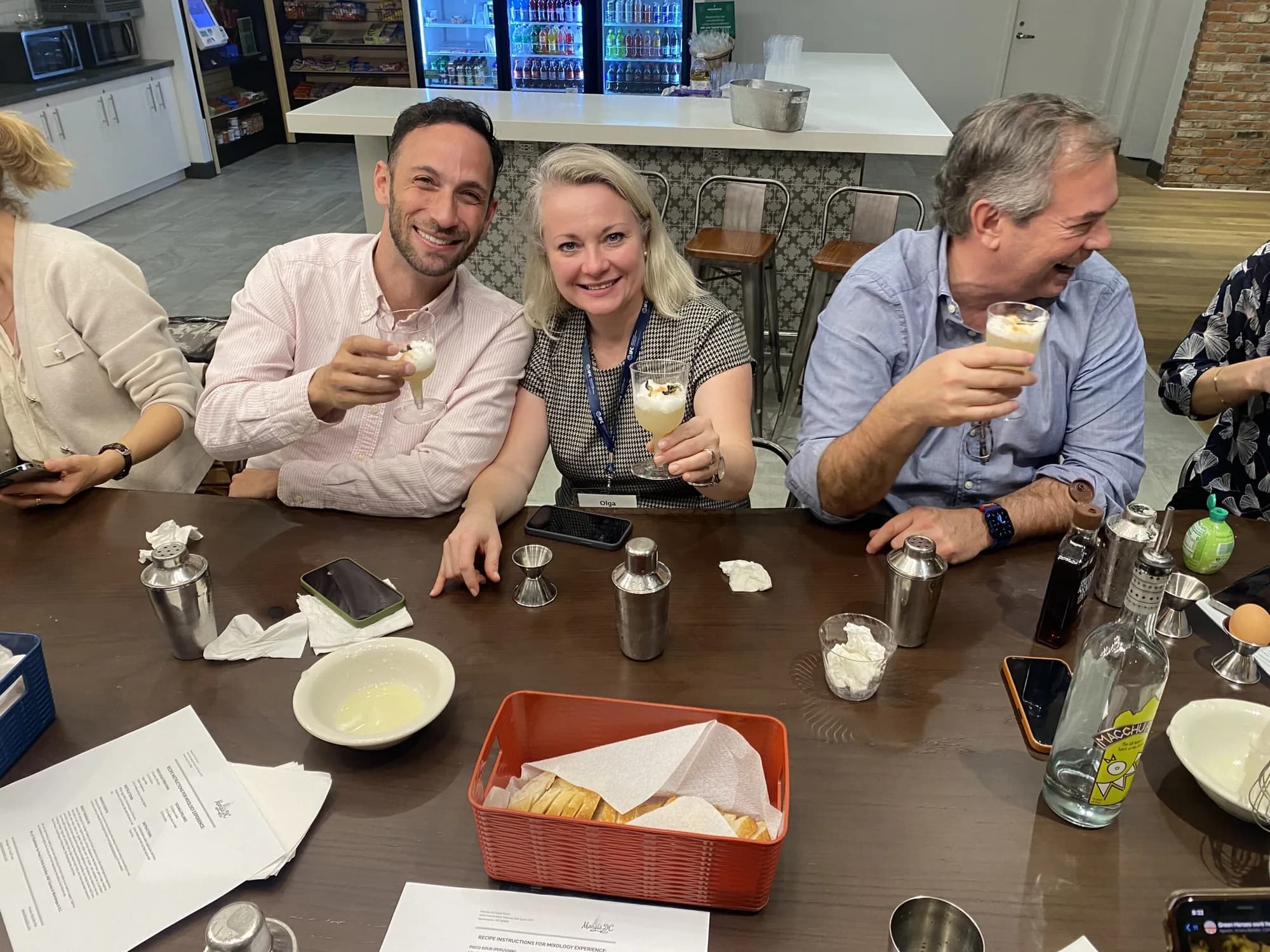 Three coworkers raising the cocktails they made at a private mixology class