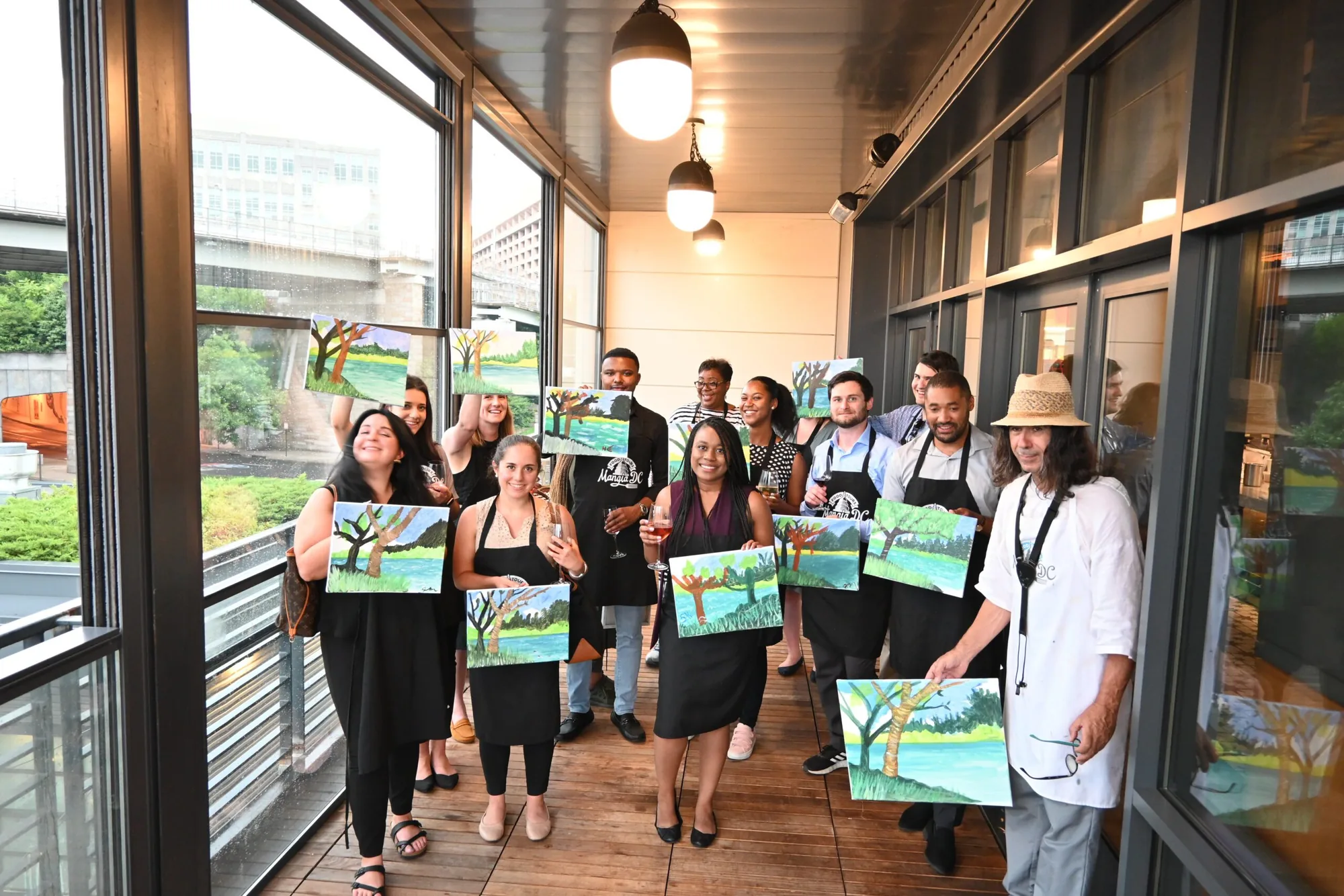Group holding their finished paintings after a private paint and sip event in Washington, DC